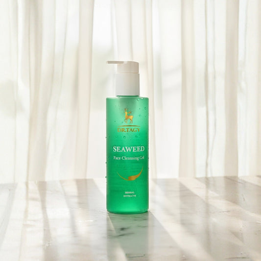 DR TAGY Seaweed Face Cleansing Gel green bottle placed on a marble surface with soft white curtains in the background.
