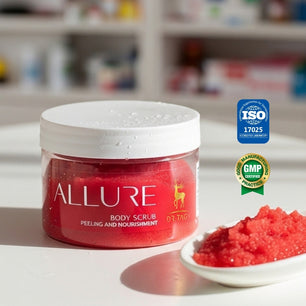 Red jar of Dr. Tagy Allure Body Scrub displayed on a white surface with a small dish of red exfoliating crystals beside it, featuring GMP and ISO certification logos — highlighting luxurious body care and natural exfoliation.