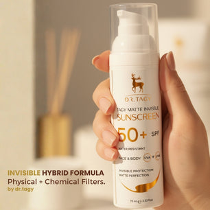 Hand holding a bottle of DR TAGY SPF50+ matte invisible sunscreen with product text partially visible in the background.